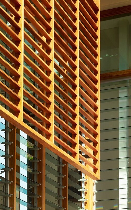 Holzlamellenelement vor Hausfassade mit verstellbaren Glaslamellen